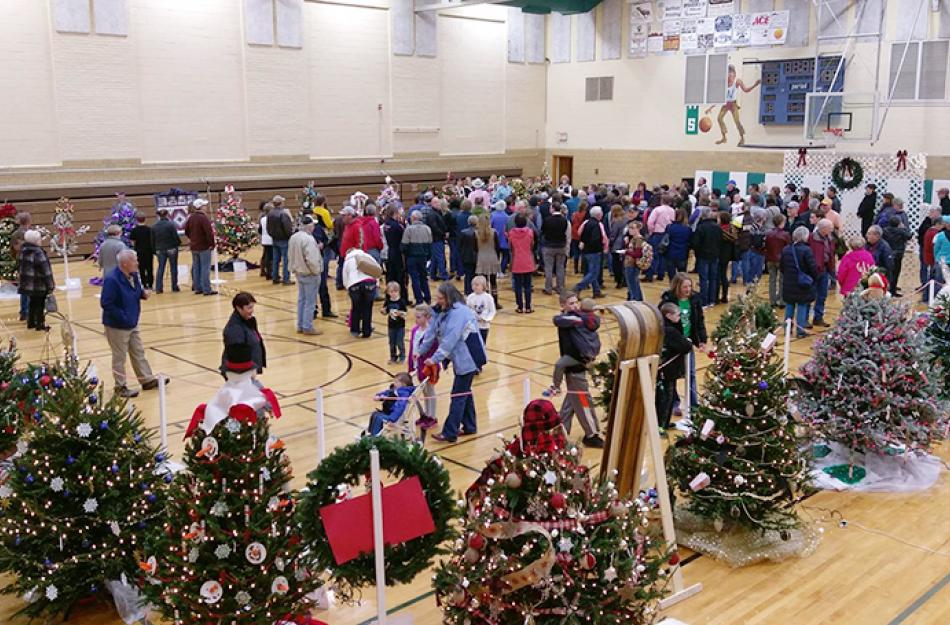 people walking around a gym filled with Christmas trees