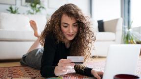 Girl laying on her stomach looking at a credit card. 