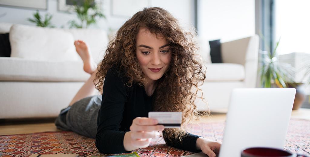Girl laying on her stomach looking at a credit card. 